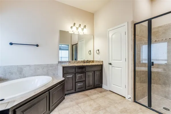 a spacious bathroom with a granite countertop sink a mirror and a bathtub