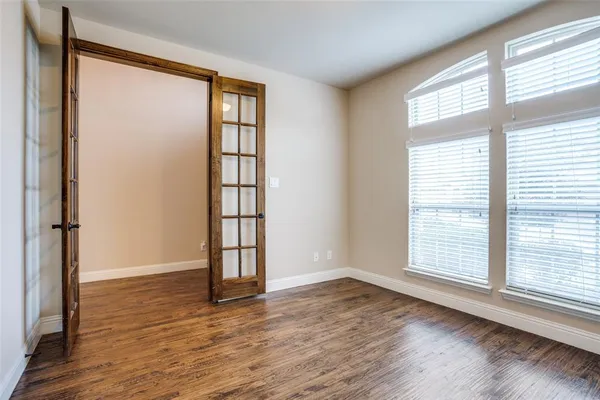 an empty room with wooden floor and windows