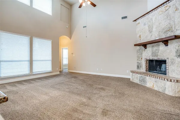 an empty room with windows and fireplace