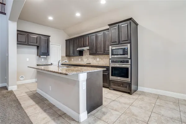 a kitchen with kitchen island granite countertop a stove top oven and cabinets