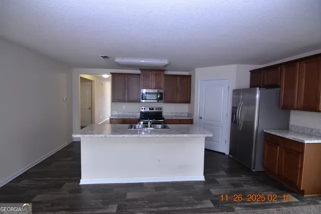 a kitchen with kitchen island stainless steel appliances a sink stove refrigerator and cabinets