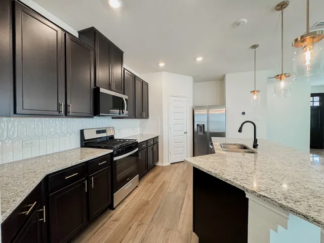 a kitchen with a refrigerator and a stove top oven