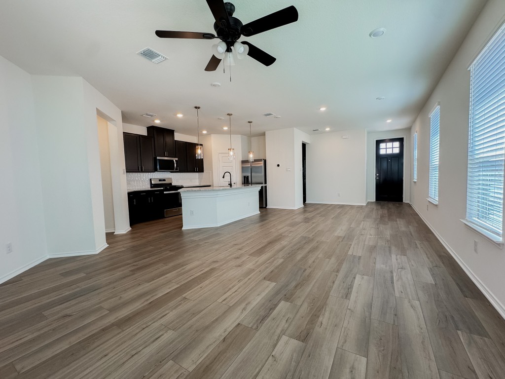 4024 Pinto Lane Round Rock, TX 78665 - Photo 7 of 31 a view of a kitchen with a stove cabinets wooden floor and a ceiling fan