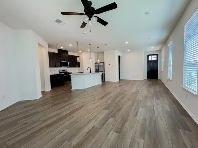 a view of empty room with wooden floor and ceiling fan