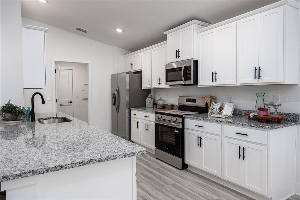 16929 Northwest 176th Way Alachua, FL 32615 - Photo 8 of 35 a kitchen with stainless steel appliances granite countertop a sink a stove and a refrigerator