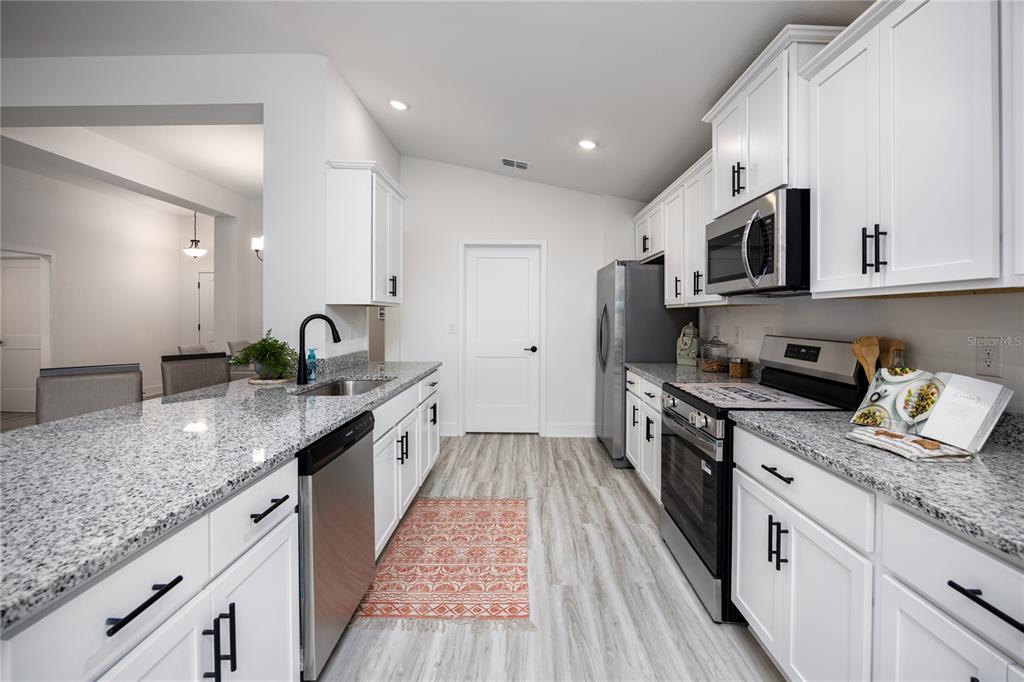 16929 Northwest 176th Way Alachua, FL 32615 - Photo 9 of 35 a large kitchen with stainless steel appliances granite countertop a lot of counter space and wooden floor