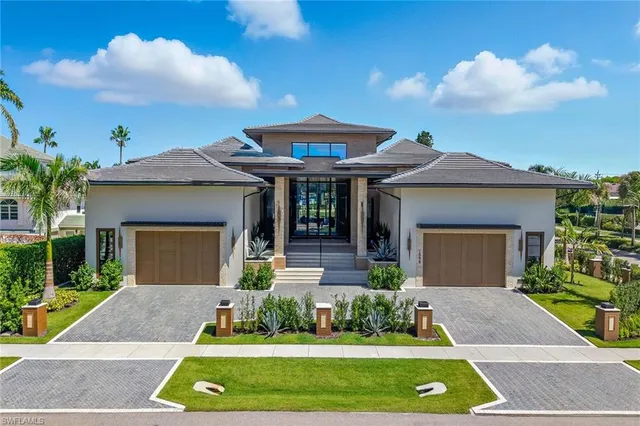 a front view of a house with a yard and potted plants