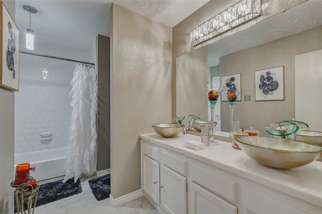 a bathroom with a granite countertop sink a mirror and shower
