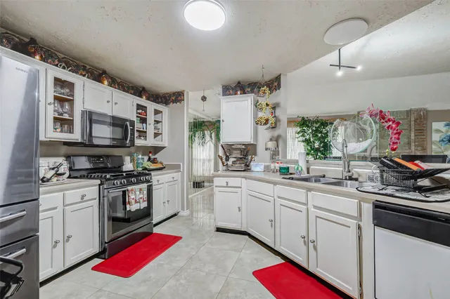 a kitchen with stainless steel appliances kitchen island granite countertop a sink dishwasher stove and white cabinets with wooden floor