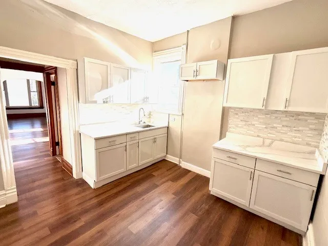a kitchen with a sink a stove cabinets and wooden floor
