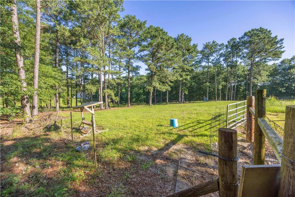 62 McCarthy Road Opelika, AL 36804 - Photo 40 of 74 Expansive green space featuring a perimeter of mature trees, a metal gate, and a wood fence line