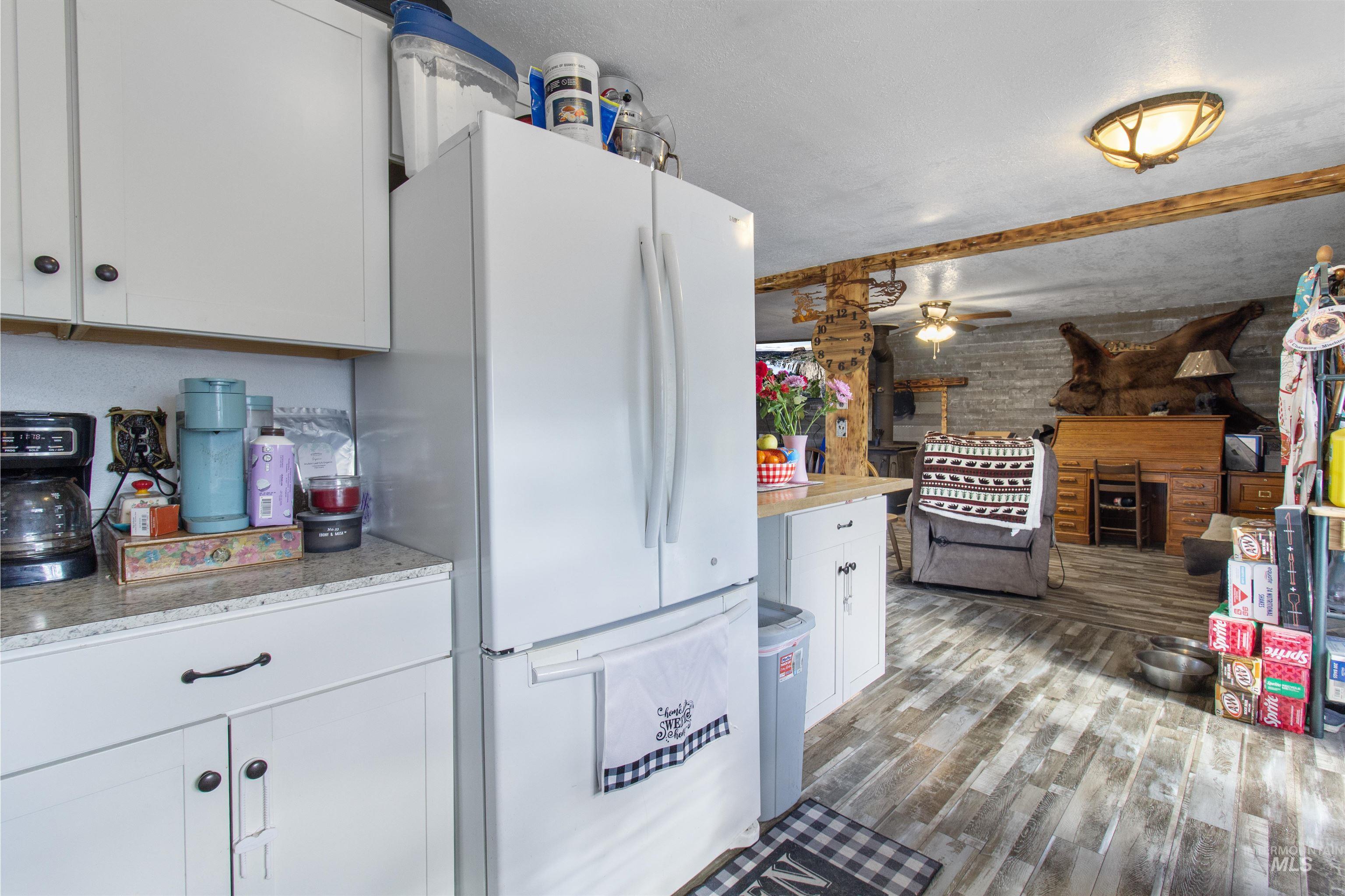 636 Main Street Hansen, ID 83334 - Photo 11 of 37 White kitchen cabinetry with dark hardware, a white refrigerator, and a speckled countertop