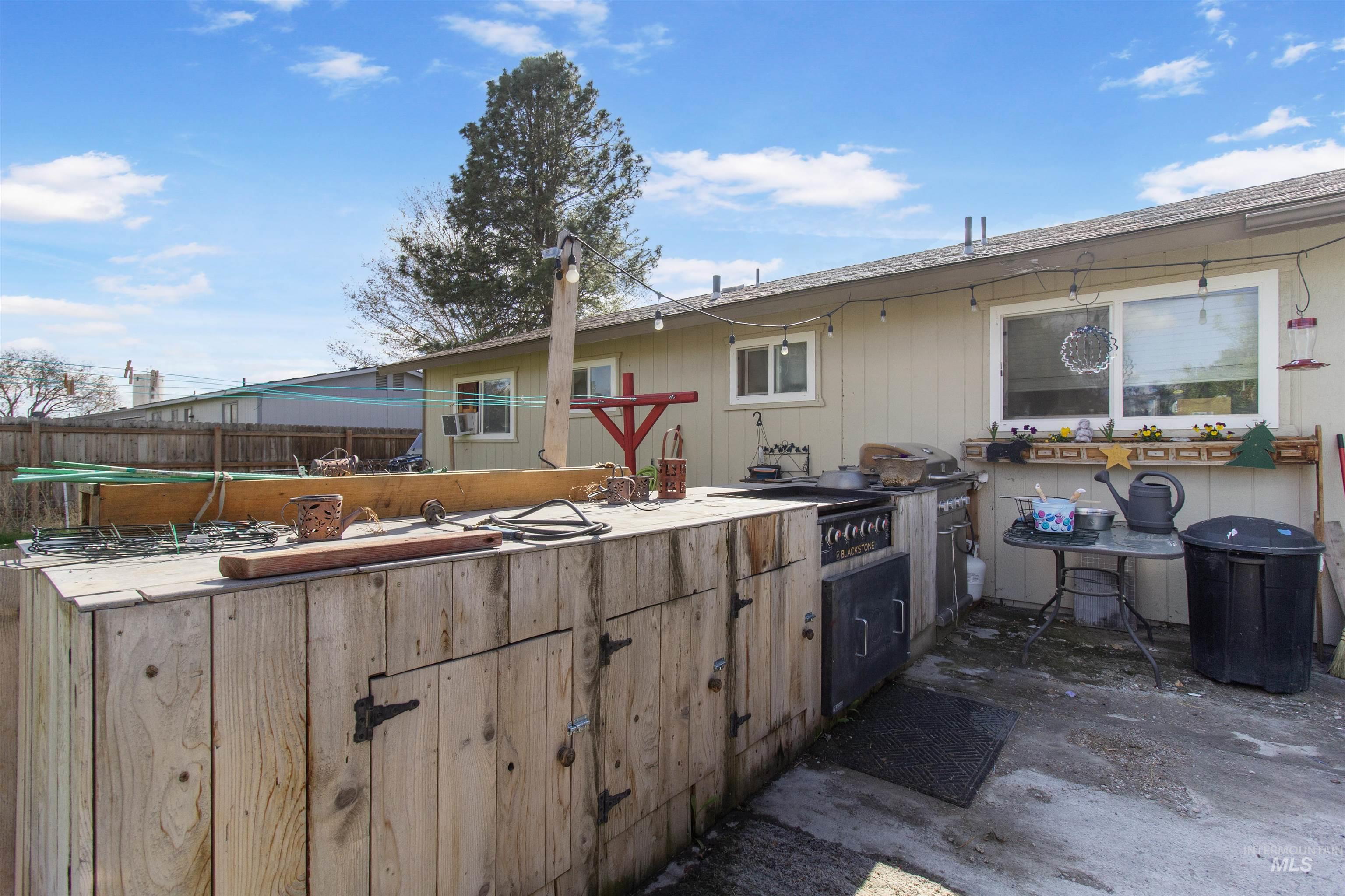 636 Main Street Hansen, ID 83334 - Photo 32 of 37 Exterior patio featuring a built-in outdoor kitchen with integrated oven and grill, a hardscape surface, exterior wall lighting, a large window, and a secondary smaller window