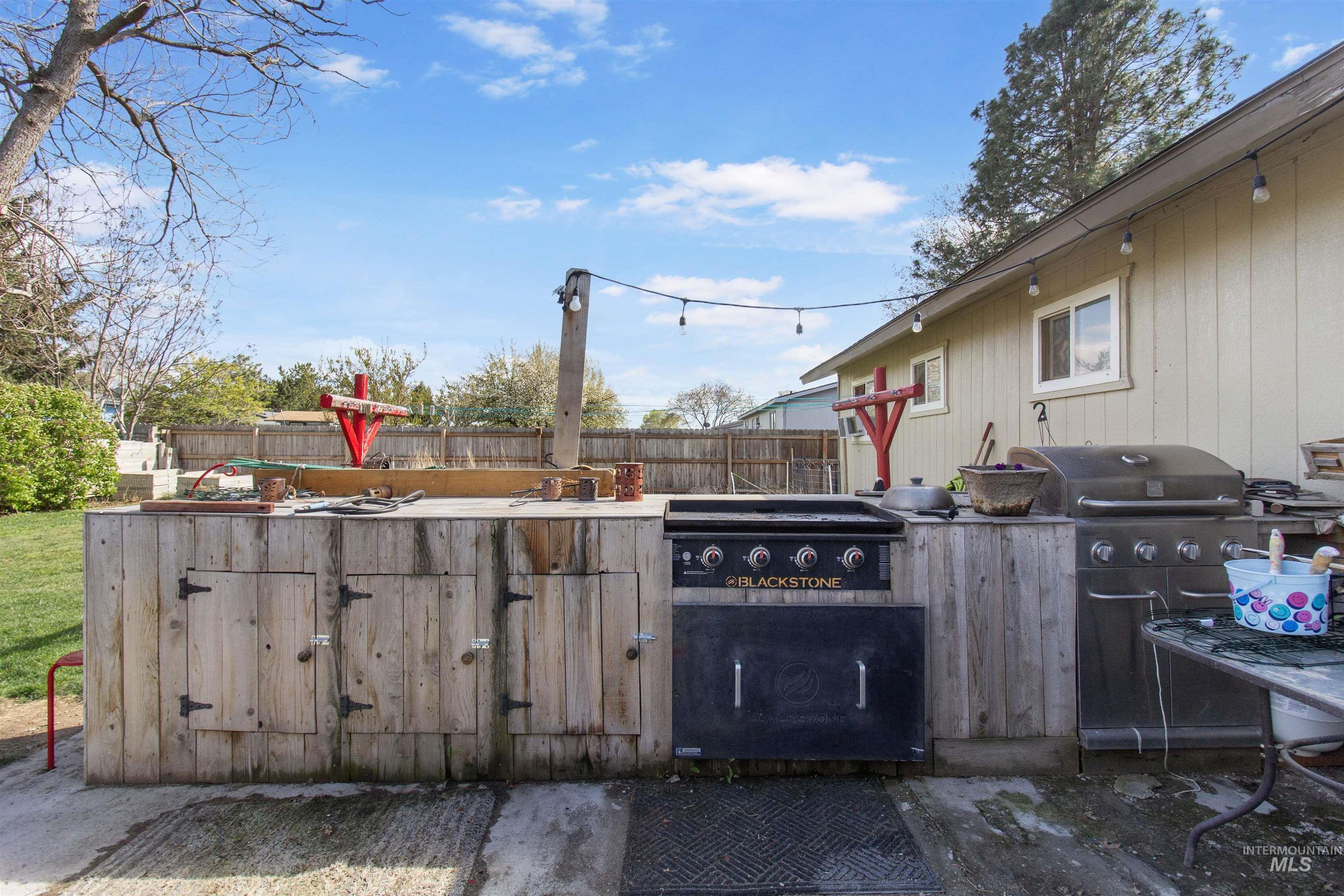 636 Main Street Hansen, ID 83334 - Photo 33 of 37 Outdoor kitchen featuring a built-in griddle, integrated grill, rustic wood-finish cabinetry, and string lighting