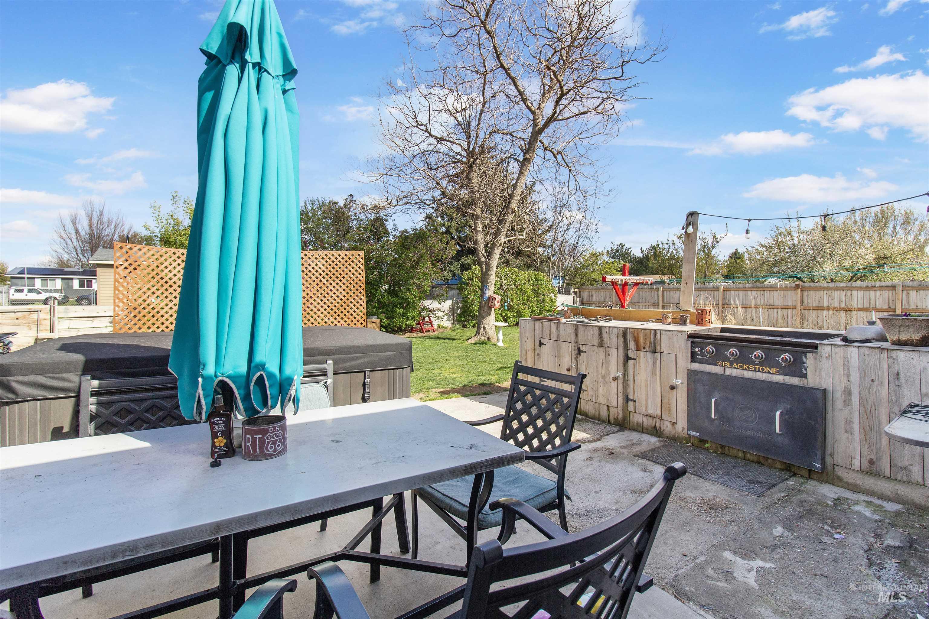 636 Main Street Hansen, ID 83334 - Photo 34 of 37 Expansive concrete patio featuring a built-in outdoor kitchen with a griddle, a covered hot tub, and a spacious lawn area