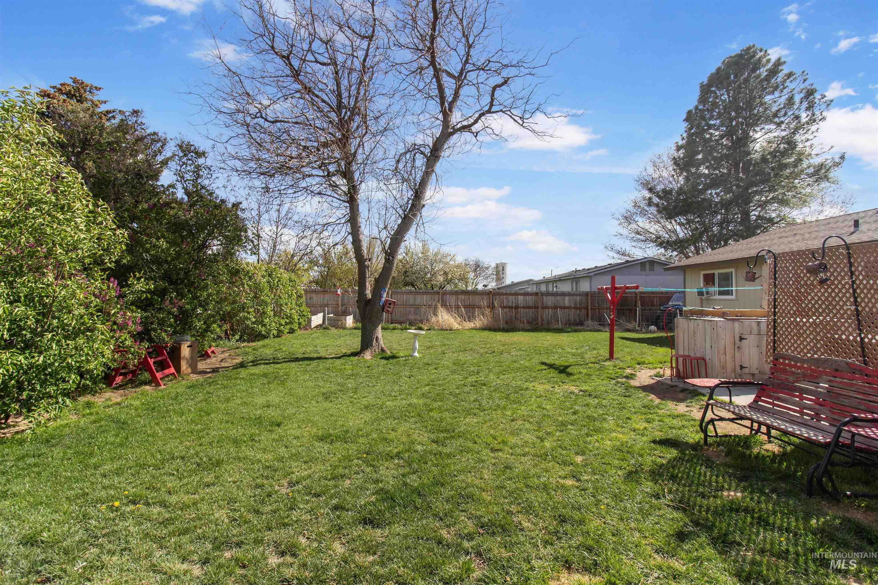 636 Main Street Hansen, ID 83334 - Photo 35 of 37 Expansive backyard featuring a lush green lawn, mature trees, and privacy fencing