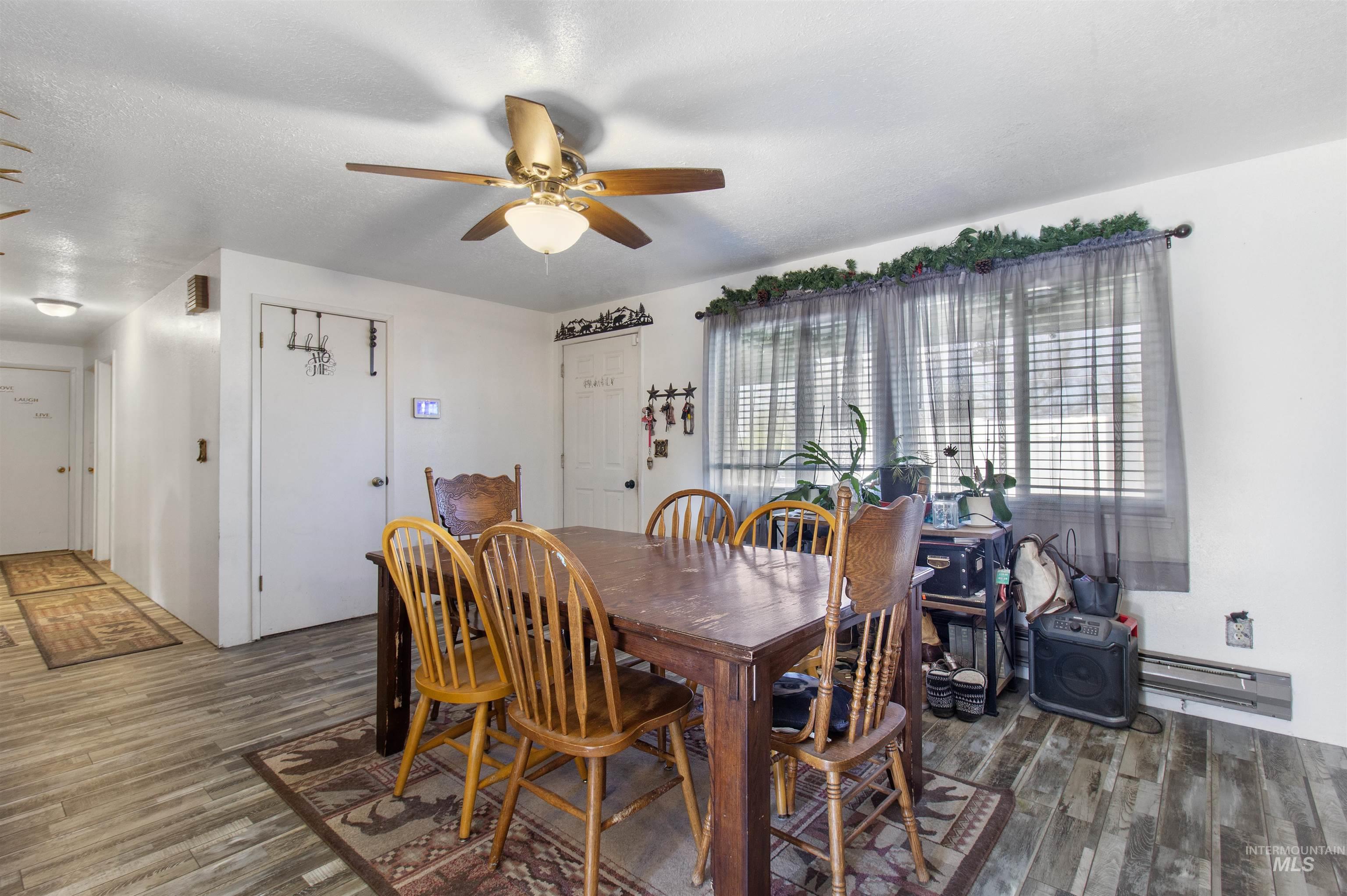 636 Main Street Hansen, ID 83334 - Photo 5 of 37 Dining area featuring wood-finish flooring, a ceiling fan with integrated lighting, and multiple windows with blinds