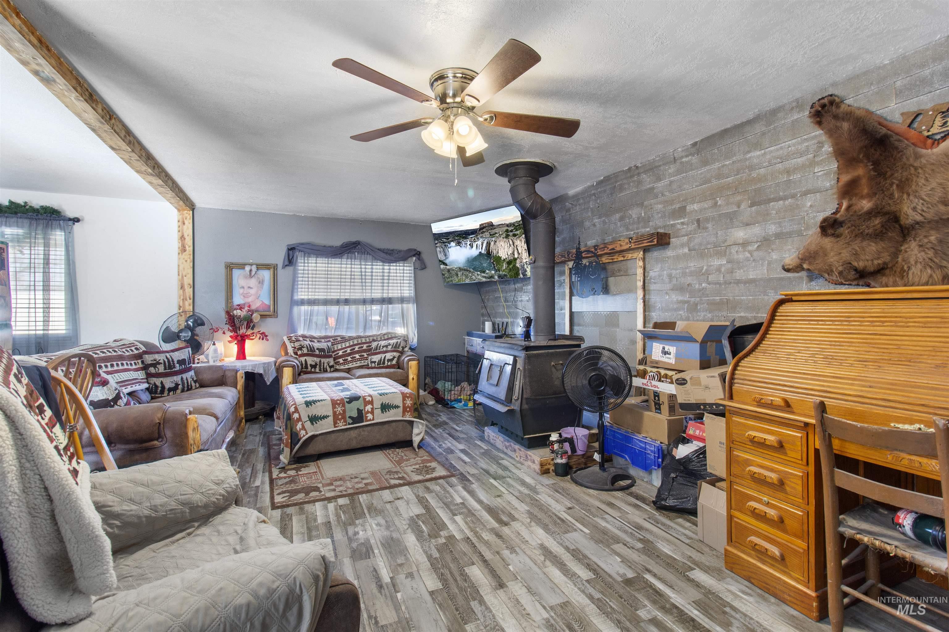 636 Main Street Hansen, ID 83334 - Photo 8 of 37 Living area featuring wood-finish flooring and a wood-burning stove with a stone-finish accent wall