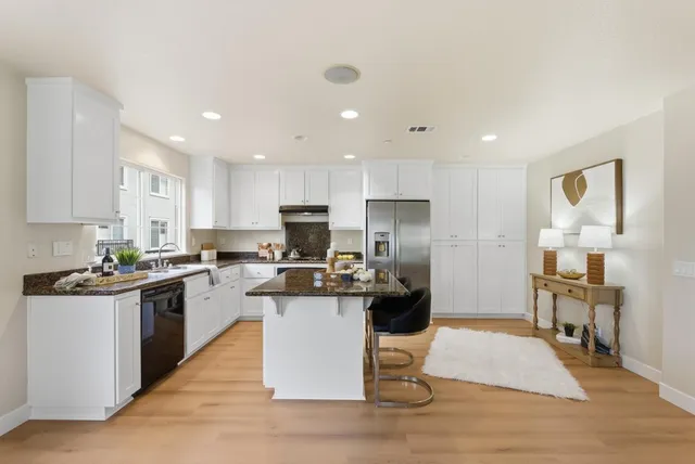 a kitchen with a sink a stove a refrigerator cabinets and a dining table