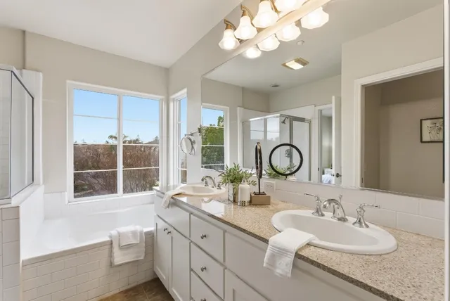 a bathroom with a granite countertop double vanity sink and a mirror