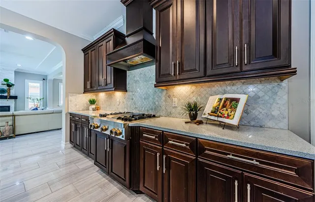 a kitchen with stainless steel appliances granite countertop a stove top oven a refrigerator a dining table and chairs with wooden floor