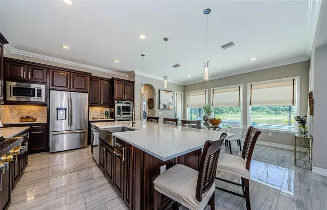 a kitchen with granite countertop a sink stainless steel appliances and furniture