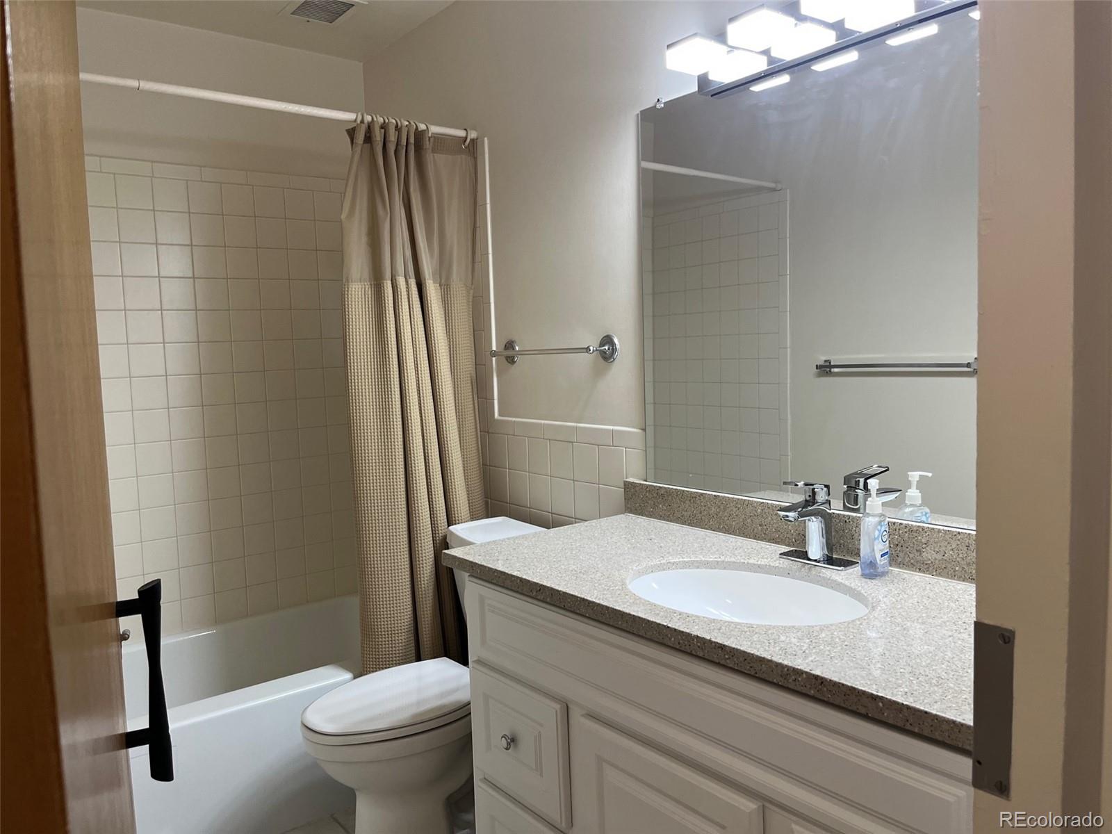 9180 Center Avenue, Unit 4D Denver, CO 80247 - Photo 18 of 19 a bathroom with a granite countertop sink toilet and shower