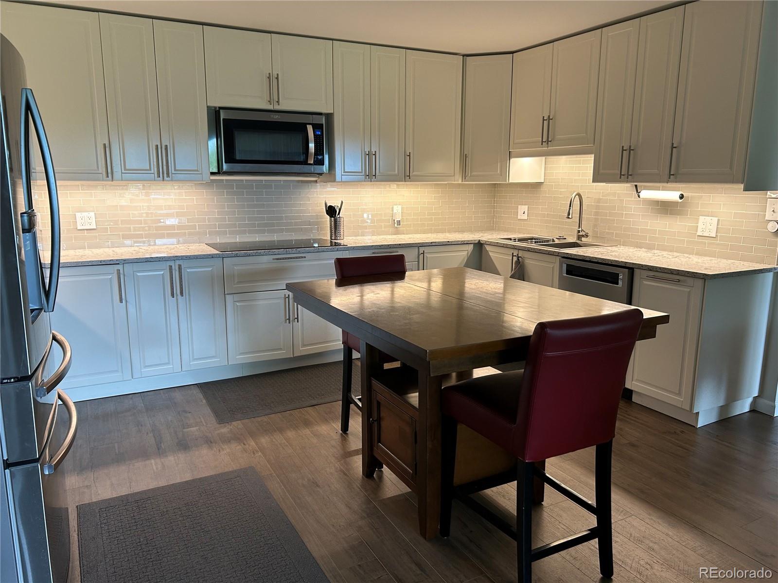 9180 Center Avenue, Unit 4D Denver, CO 80247 - Photo 2 of 19 a kitchen with stainless steel appliances granite countertop a table chairs sink refrigerator and microwave