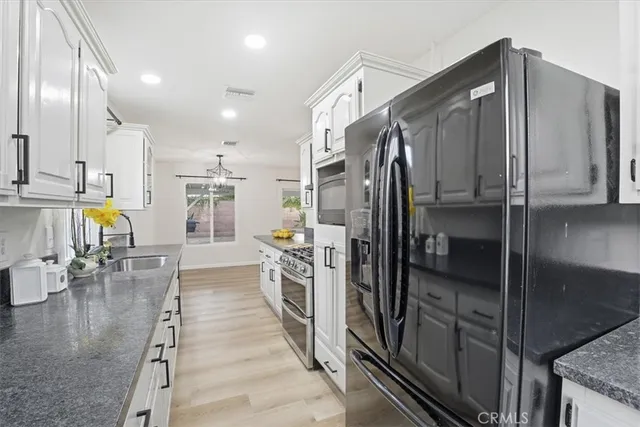 a kitchen with stainless steel appliances kitchen island granite countertop a refrigerator a stove and a sink