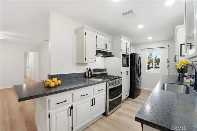 a kitchen with stainless steel appliances granite countertop a sink a stove a refrigerator a counter top space and cabinets