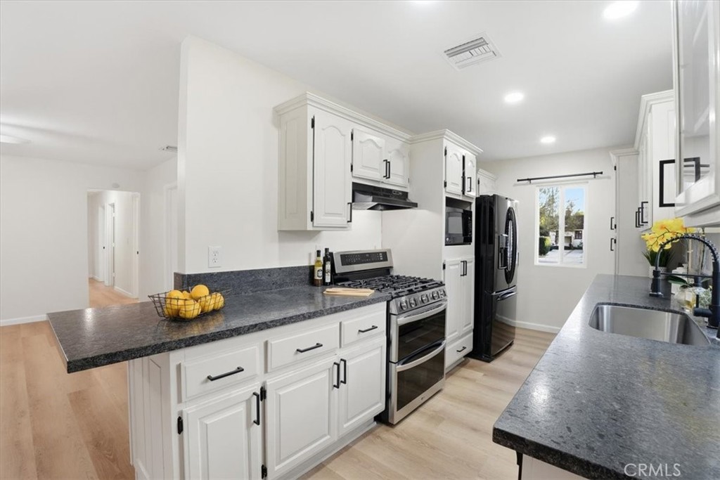 17751 Blythe Street Reseda, CA 91335 - Photo 9 of 23 a kitchen with stainless steel appliances granite countertop a sink a stove a refrigerator a counter top space and cabinets