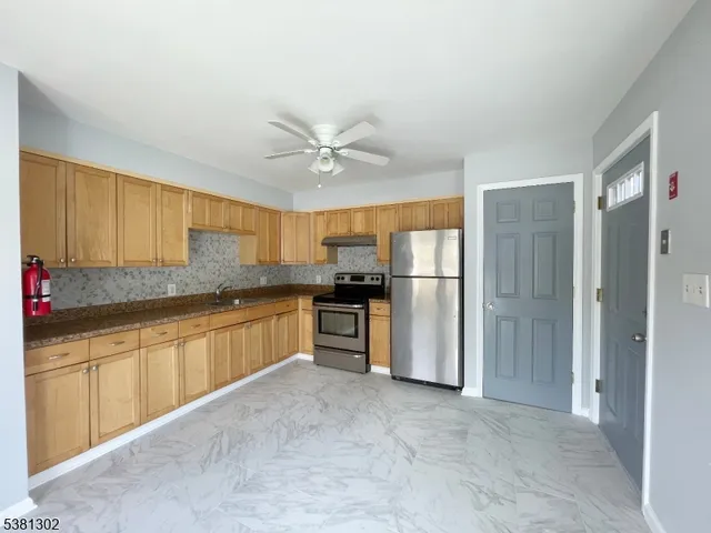 a large kitchen with stainless steel appliances granite countertop a refrigerator and a sink