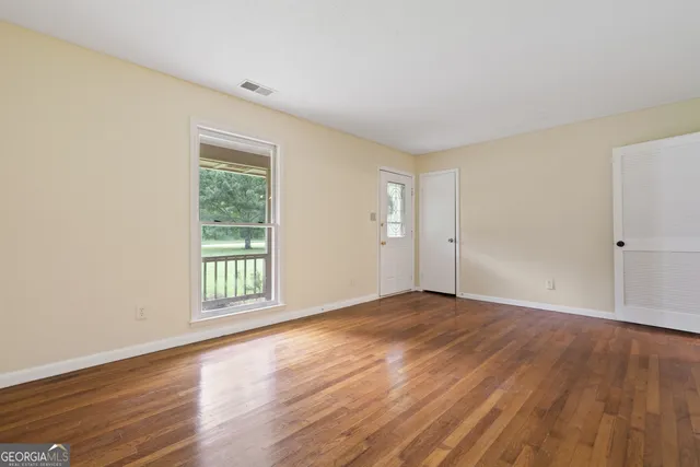 an empty room with wooden floor and windows