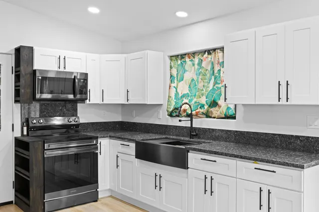 a kitchen with granite countertop white cabinets stainless steel appliances and a sink
