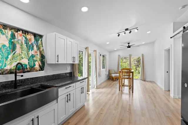 a kitchen with stainless steel appliances granite countertop a stove top oven a sink dishwasher a dining table and chairs with wooden floor