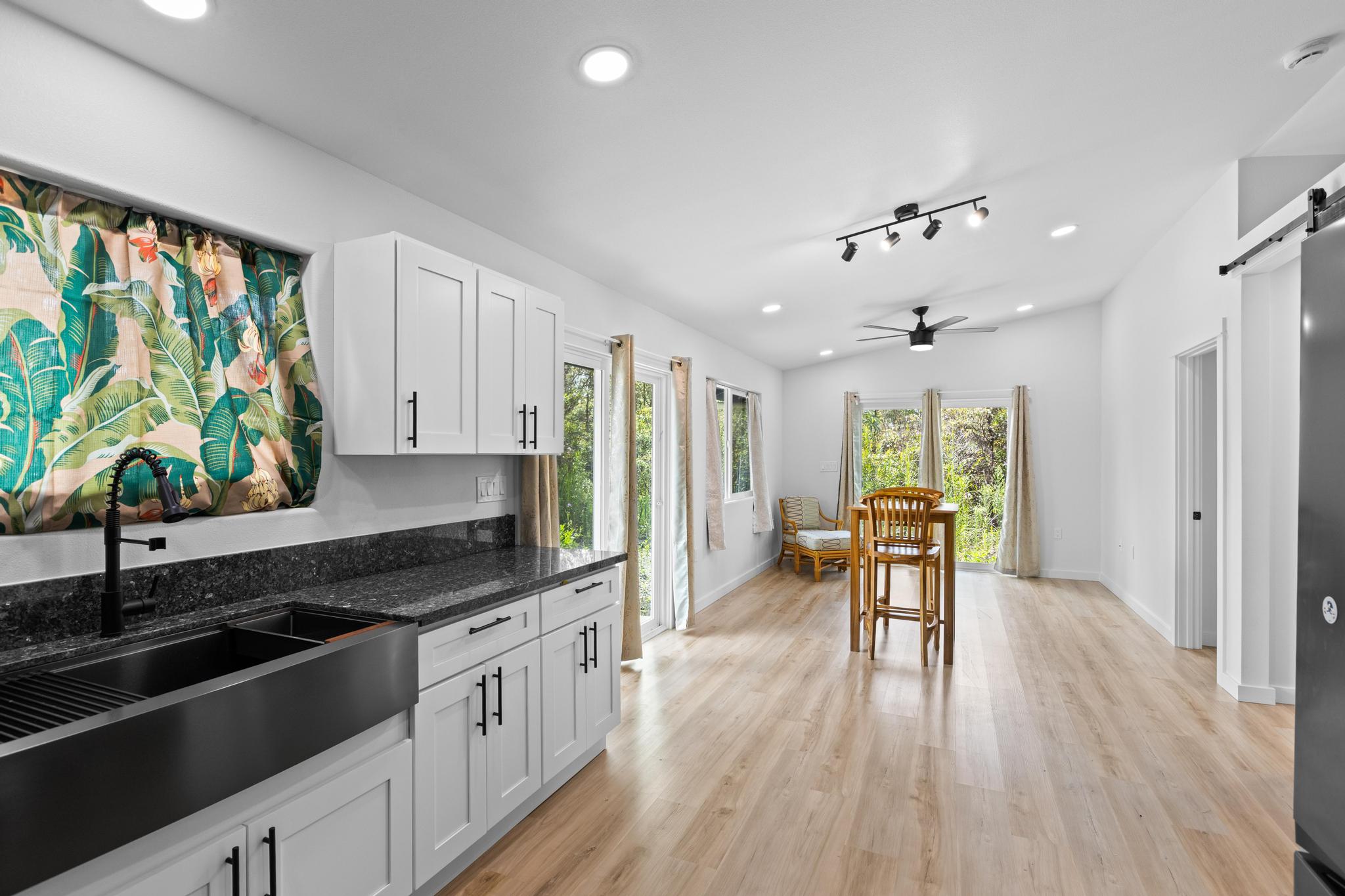 16-2075 Treefern Drive Pahoa, HI 96778 - Photo 8 of 24 a kitchen with stainless steel appliances granite countertop a stove top oven a sink dishwasher a dining table and chairs with wooden floor