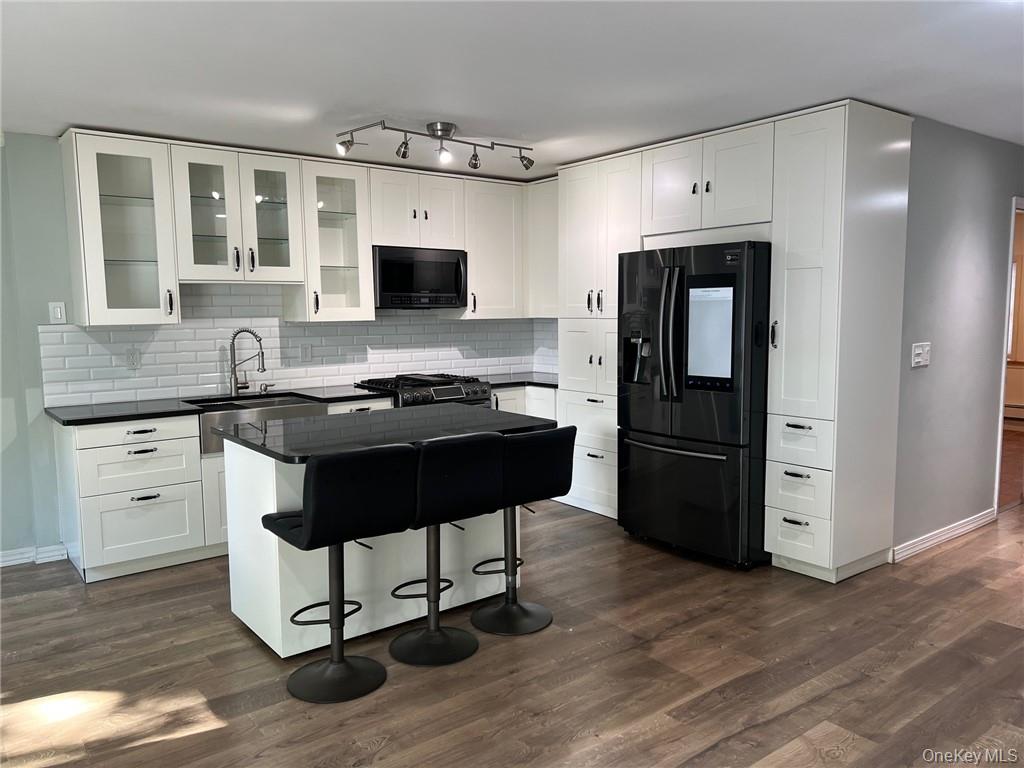 708 Silver Lake-Scotchtown Road Middletown, NY 10941 - Photo 3 of 25 Kitchen with decorative backsplash, white cabinets, black appliances, and a kitchen bar
