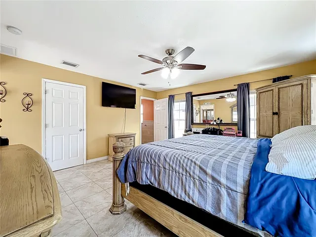 a spacious bedroom with a bed and a flat screen tv