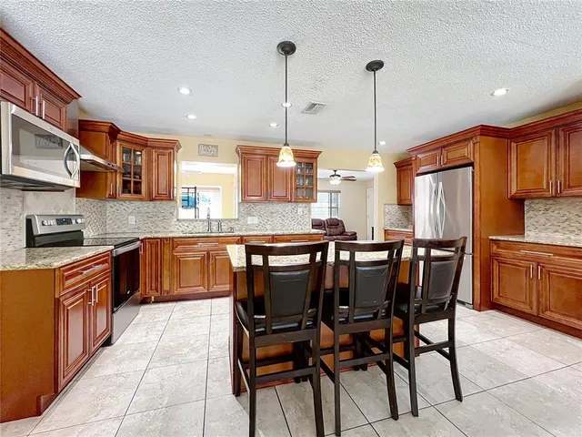 a kitchen with stainless steel appliances granite countertop table chairs sink and cabinets