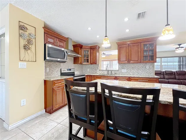 a kitchen with stainless steel appliances granite countertop a sink a stove a microwave a refrigerator and cabinets