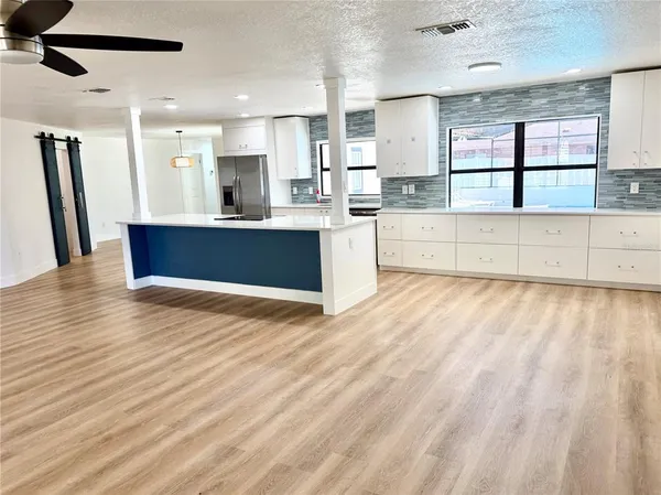 a large kitchen with stainless steel appliances kitchen island granite countertop a large counter top a stove a sink and a refrigerator