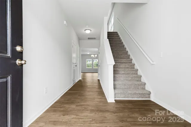 a view of a hallway with wooden floor and staircase