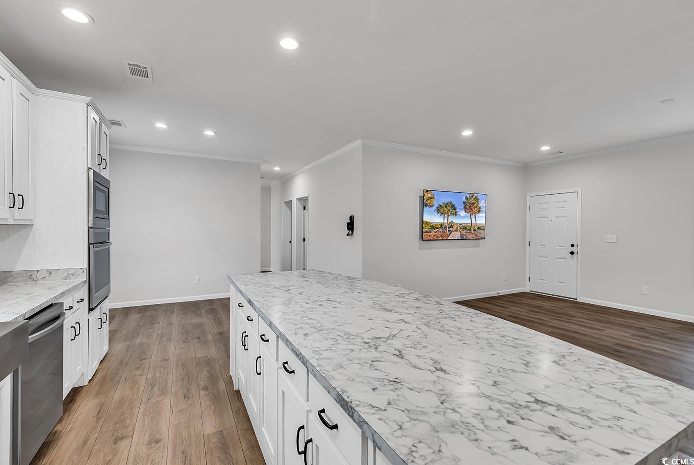 1529 Bucksport Road Conway, SC 29527 - Photo 15 of 31 Kitchen featuring crown molding, light wood-style flooring, light countertops, stainless steel fridge, and white cabinets