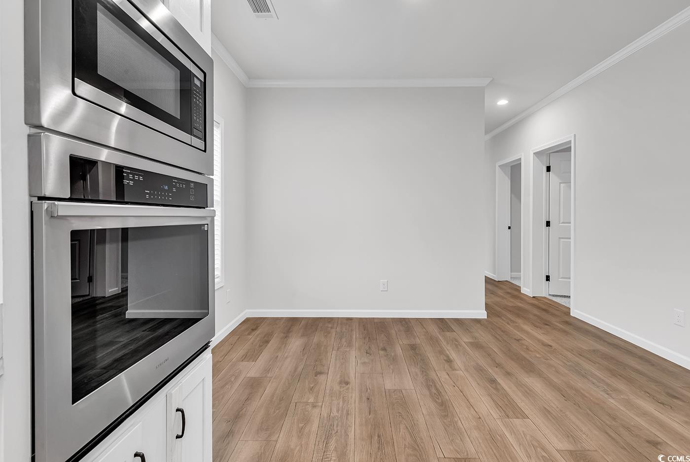 1529 Bucksport Road Conway, SC 29527 - Photo 16 of 31 Kitchen with light wood finished floors, white cabinets, recessed lighting, ornamental molding, and stainless steel appliances
