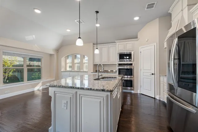a large kitchen with cabinets wooden floor and stainless steel appliances