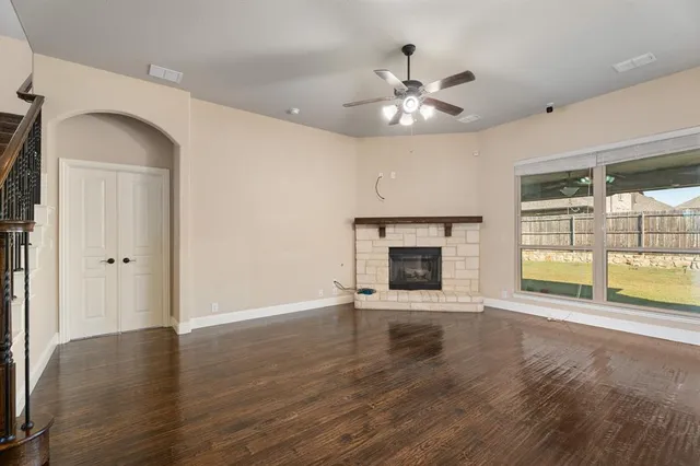 an empty room with wooden floor fireplace and windows
