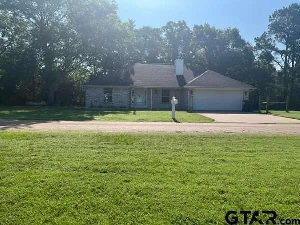 a view of a house with a yard and a large tree