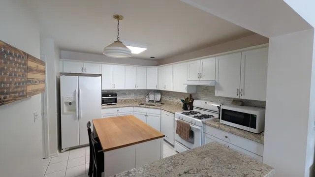 a kitchen with stainless steel appliances granite countertop a stove refrigerator sink and microwave