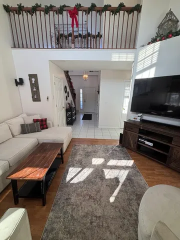 a living room with furniture a flat screen tv and a refrigerator