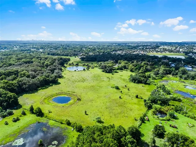 an aerial view of a residential houses with trees in the background
